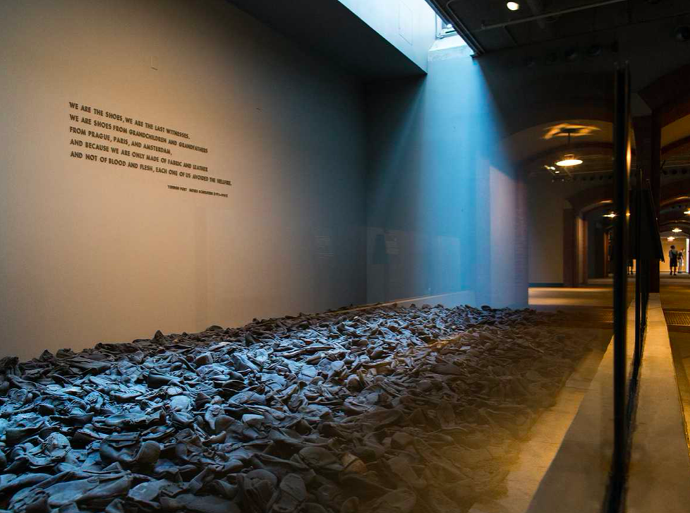 Figure 1. One of the shoe piles with Shulstein’s poem excerpt in English above the shoes. https://huntnewsnu.com/46292/editorial/editorial-holocaust-statement-should-be-alarming/